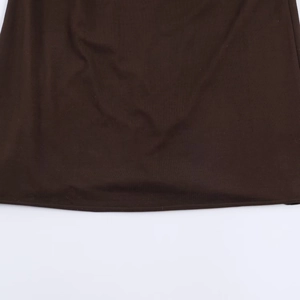 Detail of dark brown knitted dress featuring soft draped hemline and fine ribbed texture