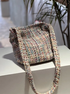 Macro view of multi-color woven tweed knit texture and brand label on a shoulder bag