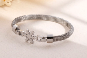 Détail d'un bracelet en maille argentée avec un motif de flocon de neige sur fond texturé