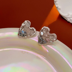 Gros plan de boucles d'oreilles cœur argentées avec cristaux sur plateau irisé