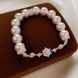Elegant pearl bracelet with silver snowflake zircon charm on a brown velvet jewelry box