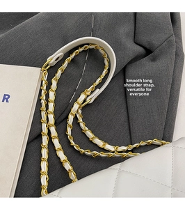 Close-up of a white quilted leather bag with a gold metal chain and leather strap details