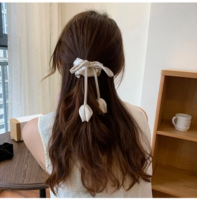 Close-up of beige fabric scrunchie with long ribbons and tulip bud charms on a model