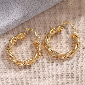 Detailansicht goldener Creolen mit gedrehter Seilstruktur und mattem Metall-Finish