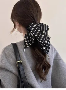 Détail d'un chouchou à rayures noires et blanches avec perles sur une queue de cheval basse