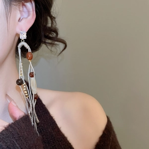 Close-up of bohemian tassel earrings with zircon studs worn by a model in lifestyle shot