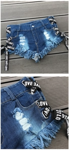 Dettaglio di pantaloncini di jeans blu con orli sfrangiati, strappi e allacciatura LOVE