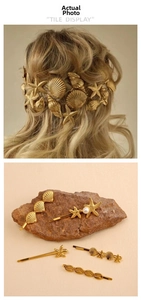 Close-up of golden starfish and seashell hairpins with pearls on a natural rock background