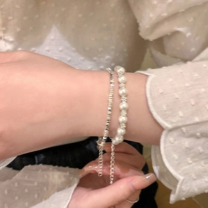 Detail view of double-layer beaded bracelet featuring white pearls and silver metal beads