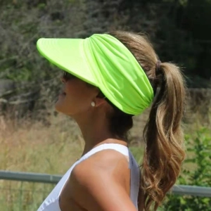 Side view of a fluorescent green visor sun hat on a model in a natural outdoor setting