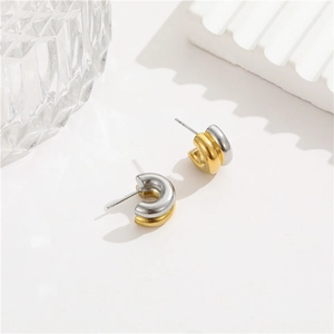 Minimalist C-shaped two-tone stud earrings in gold and silver finish on a clean surface
