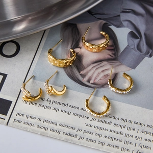 Trois paires de boucles d'oreilles créoles C en acier titane doré avec zircon sur papier