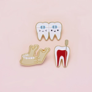 Set of three dental enamel pins featuring teeth with braces and root canal structures