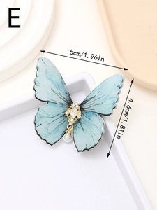 Macro detail of butterfly hair clip with blue wings, faux gems and a pearl drop