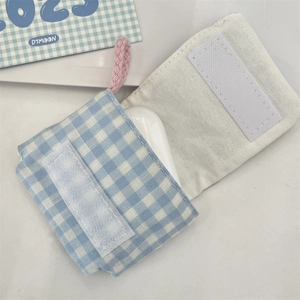 Detalle de mini funda para auriculares de cuadros azules con forro suave y cordón rosa