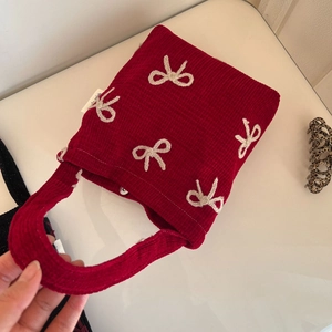 Détail du sac à main en velours rouge avec nœuds blancs et fermoir magnétique en argent