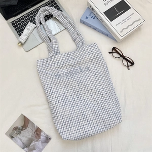 Flat lay of blue checkered canvas tote bag with Sozakka embroidery and ruffled handle