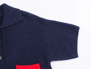 Detailed close-up of navy knit cardigan with contrasting red pocket and ribbed collar