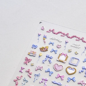 Detailed close-up of 3D embossed nail art stickers with pastel bows and heart designs