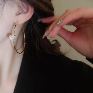 Détail d'un mannequin portant des créoles dorées en C avec zircons en forme de cœur