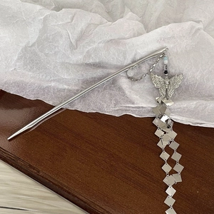 Silver vintage hair pin with butterfly motif and square metal tassel on wood background