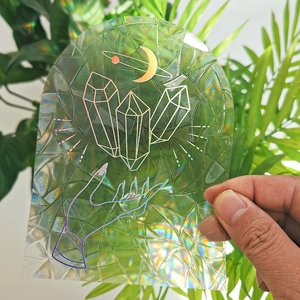 Holographic suncatcher sticker with crystal, palm, and crescent moon in rainbow light