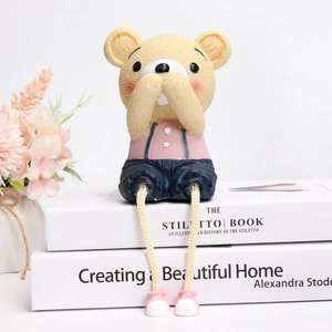 Detail of cute resin bear figurine with pink top and rope legs sitting on books