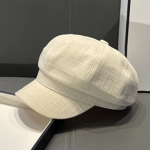 Close-up of beige newsboy hat showing detailed jacquard check texture on fabric