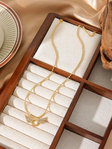 Close-up of a 18k gold plated wing pendant necklace with zircon in a wooden jewelry box