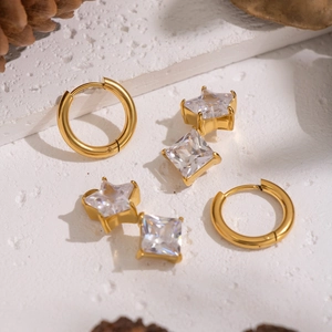 Golden earrings set with star and square studs and hoops featuring clear zircons
