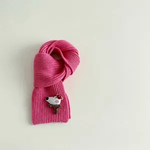 Detail of rose red ribbed knit scarf with a cute 3D cartoon bear patch and soft texture