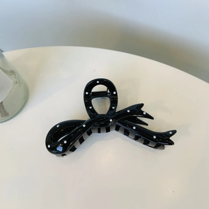Detail of a large bow hair claw clip featuring a black and white polka dot pattern design