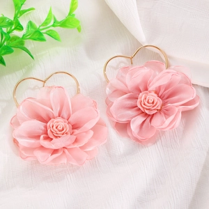 Dettaglio macro di orecchini a fiore in tessuto rosa con ganci in metallo a cuore oro