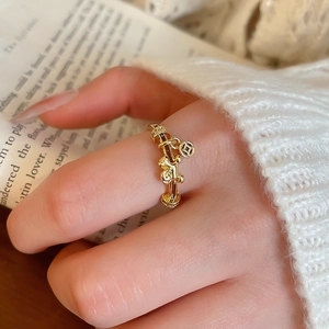 Macro detail of gold plated ring featuring a small pony charm and abacus beads on finger