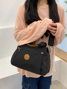Black canvas crossbody bag with brown leather handles and adjustable wide strap