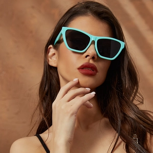 Close-up of mint green cat-eye sunglasses with dark lenses on a stylish female model