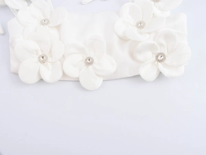 Nahaufnahme weißer 3D-Stoffblumen mit funkelnden Strasssteinen auf dem Haarschmuck