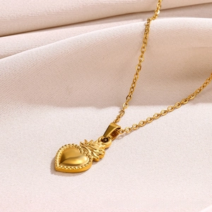 Detailed view of vintage style 18k gold heart pendant with flame pattern on fine chain