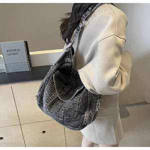 Détail d'un sac à bandoulière en denim noir délavé avec sangle réglable sur le mannequin