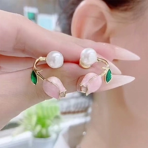 Pink tulip pearl earrings with gold stem and green leaf detail worn by a model