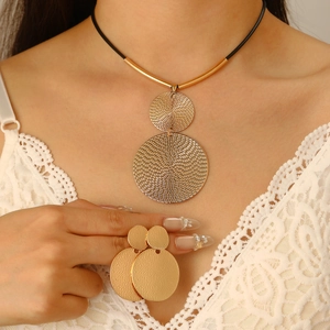 Close-up of golden geometric disc pendant necklace and matching earrings on a model
