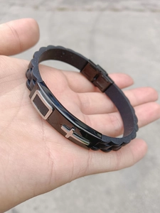 Close-up of black silicone sport bracelet with black metal plate and silver cross inlay