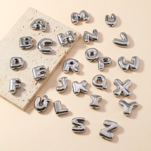 Detail of silver bubble letters for DIY jewelry making on a textured stone plate