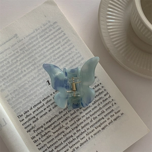 Close-up of a blue and white gradient butterfly hair claw clip on an open book page