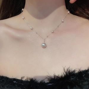 Close-up of irregular pearl pendant necklace with silver chain on black feather dress