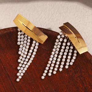 Détail de boucles d'oreilles à pompons plaquées or 18K avec métal brossé et zircons