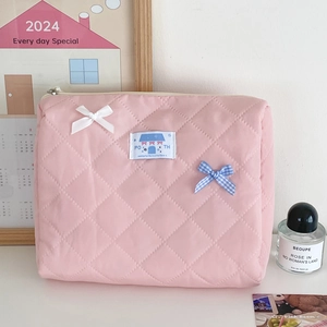 Detailed shot of pink quilted makeup bag with bow accents and soft diamond pattern textures