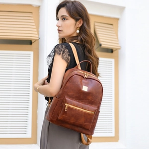 Detail of a dark brown faux leather backpack with vintage texture shown on a female model