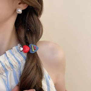 Detailed close-up of a three-heart hair clip featuring blue denim, red, and silver textures