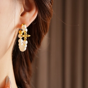 Detail of vintage 18K gold plated pearl hoop earrings with a central golden cross flower